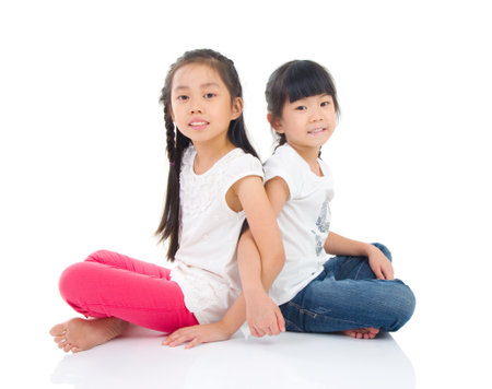 Asian sisters sitting on the floorの写真素材