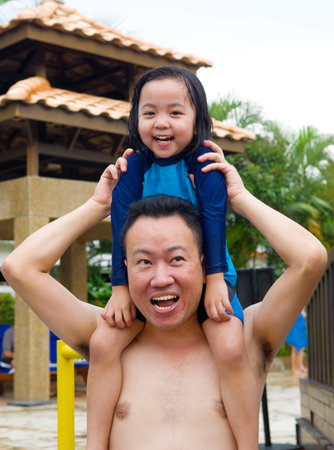 Man carrying his little daughter on shoulders in swimming poolの写真素材