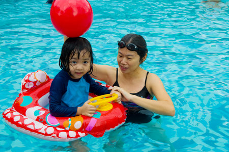 asian family in swim tube playing on swimming poolの写真素材