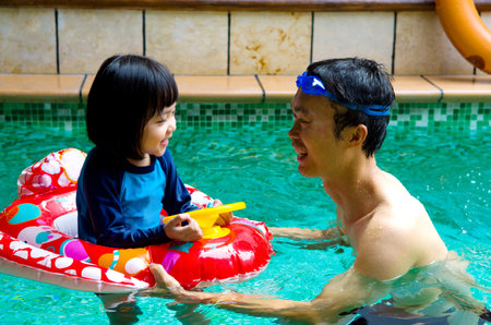 asian family in swim tube playing on swimming poolの写真素材