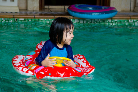 asian child in swim tube playing on swimming poolの写真素材