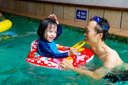 asian family in swim tube playing on swimming poolの写真素材