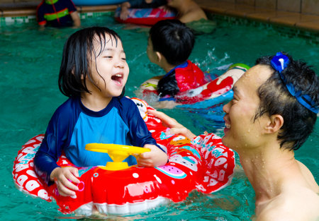 asian family in swim tube playing on swimming poolの写真素材