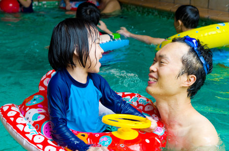 asian family in swim tube playing on swimming poolの写真素材