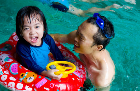 asian family in swim tube playing on swimming poolの写真素材