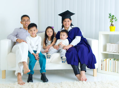 Asian mother in graduation gown.Taking photo with family.の写真素材