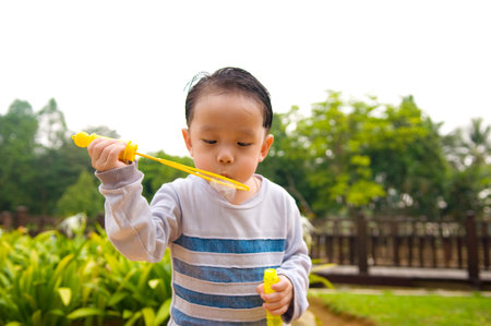 Asian boy blowing bubbles outdoorの写真素材