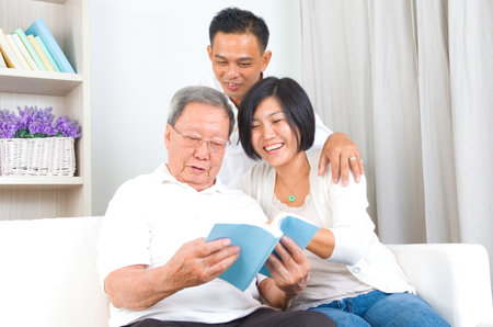 Asian family reading book at homeの写真素材