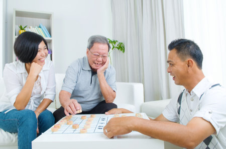 Chinese family playing Chinese chess at home, senior father with his  adult son and daughter.の写真素材