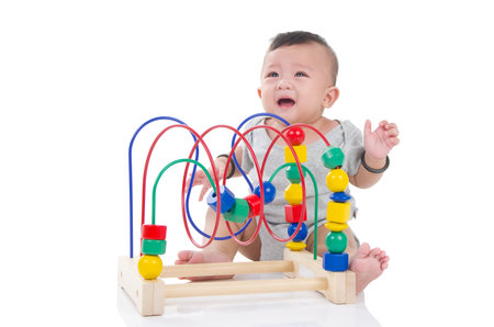 Cute asian boy crying and sitting on the floor, playing with toy.の写真素材