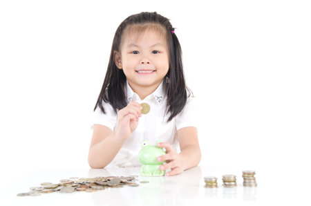 Asian little girl saving money in a piggy bank,education and money saving concept. Isolated on white backgroundの写真素材