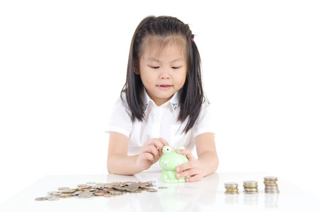 Asian little girl saving money in a piggy bank,education and money saving concept. Isolated on white backgroundの写真素材