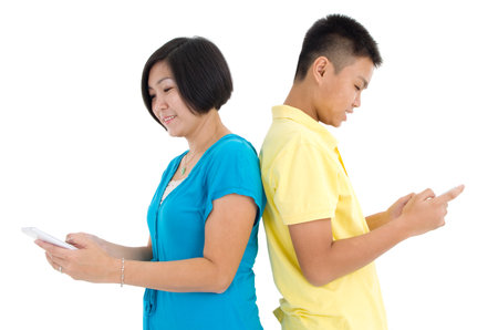 Mother and her son busy with smartphones at homeの写真素材
