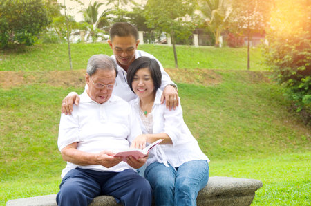 Asian family reading book at outdoor parkの写真素材