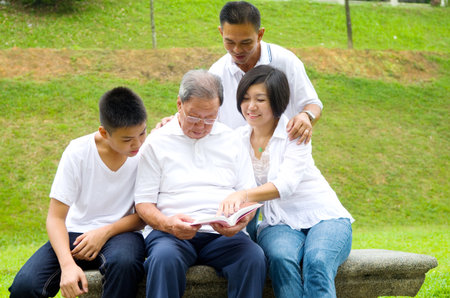 Asian three generation family reading book at outdoor parkの写真素材