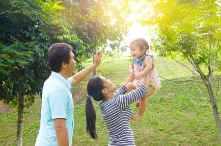 Happy Asian family playing in park during summer sunset, outdoors shot.の写真素材