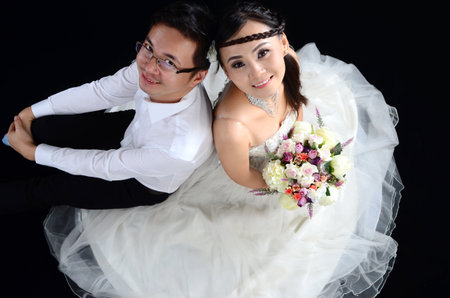 Portrait of young elegant enamoured just married groom and bride embracing at Wedding on black backgroundの写真素材