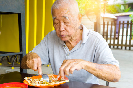 asian senior man having roti canai outdoorの写真素材