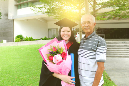 Asian university student and father celebrating graduation outdoorの写真素材