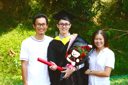 Asian university student and family celebrating graduation outdoorの写真素材