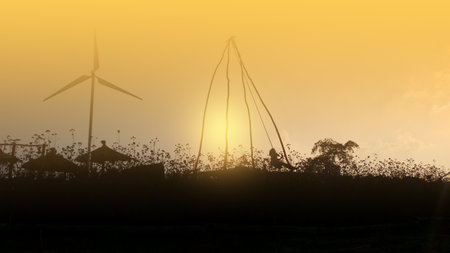 Child playing in a field at sunset with a windmill.の写真素材