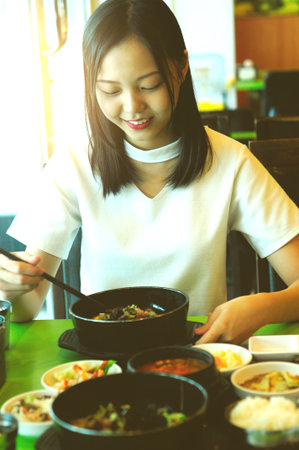 beautiful young asian girl eating korean food for lunch in a restaurant.の写真素材