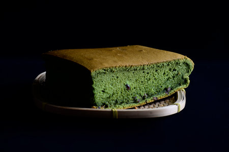 Matcha sponge cake  on wooden basket isolated on black backgroundの写真素材