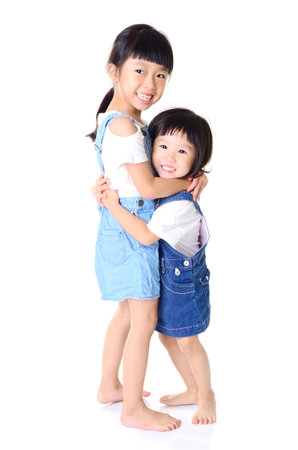 Portrait of young asian sisters with arms around each other smilingの写真素材