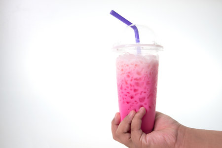A beautifully colored drink in a glass on the hand of someone holding a white backdrop.の写真素材