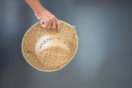 Hand of a man holding a hat against a gray backdrop.