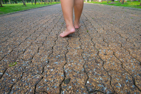 The man was walking on the road barefoot in the park.