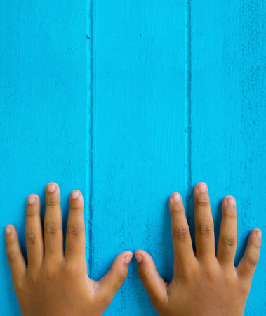 The finger and nail of a young child on a blue wooden floor.の写真素材