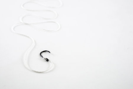 Single hook black fishing hook with white rope on a white background.の写真素材
