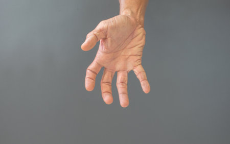 The gesture of rough hands and wrinkles of the elderly on a gray background.
