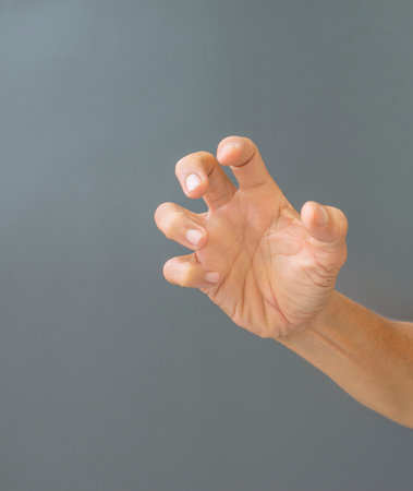 The gesture of rough hands and wrinkles of the elderly on a gray background.
