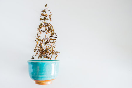 Dried tea leaves with a cup of tea on a white background.の写真素材