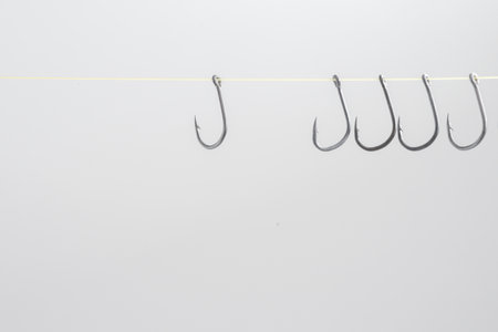 Hooked hooks with yellow ropes hang many together on a white background with empty space.の写真素材