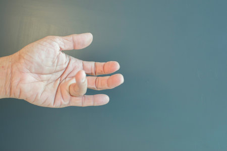 The fingers of the elderly with problems of arthritis, bones and nerves on a gray background