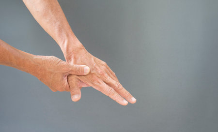Hands and bones, joints of the fingers with the problems of the elderly on a gray background with free spaceの写真素材