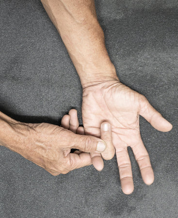 An image of an elderly person's hand and finger gestures on a gray-black background.の写真素材