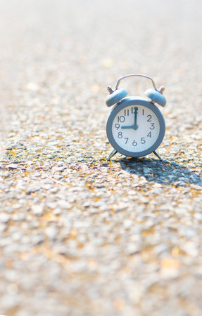 The clock is on a concrete floor in an outdoor location.の写真素材