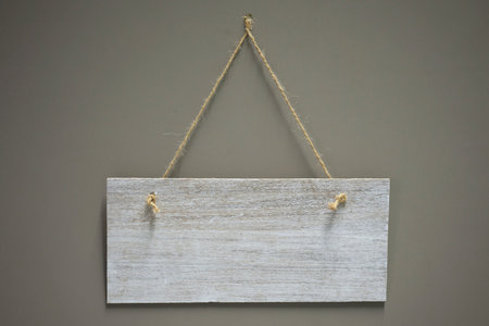 Vintage wooden sign with rope hanging on a gray backgroundの写真素材