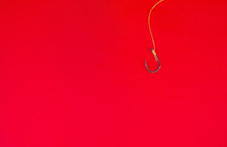 Many fishing hooks hang together with a red background and empty space.の写真素材