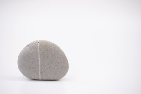 A picture of a single pebble in a round shape, according to natural characteristics on a white area.