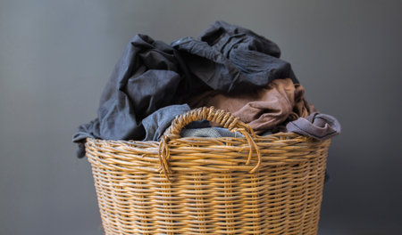 Clothes in a basket rests against a gray backdrop.