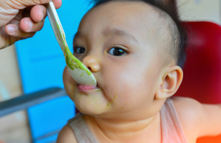 Face and gesture expression of Asian babies during eating time.の写真素材