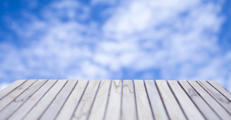 Display a wooden deck on a background of brightly colored clear skies and clouds.の写真素材