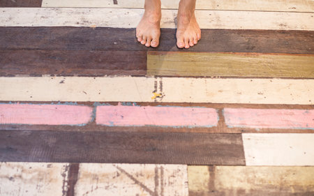 Human feet standing on colorful old wooden floorの写真素材