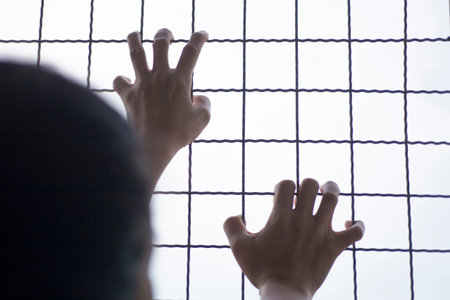 A person holding on to the wall of the steel barricadeの写真素材