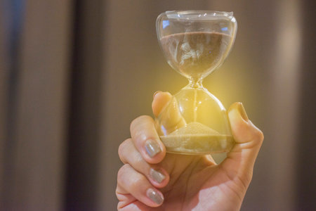 Person's hand holding an hourglass still life
